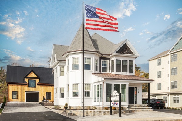 Residential property with American flag prominently displayed on flagpole, showcasing curb appeal and pride, in context of professional flagpole installation services by Signs East.
