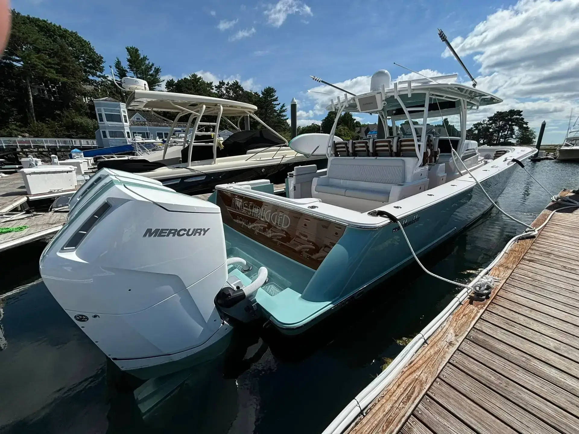 Center console boat with Mercury outboard motor docked at marina, showcasing sleek design and spacious seating, relevant for custom boat wraps and graphics services by Signs East.