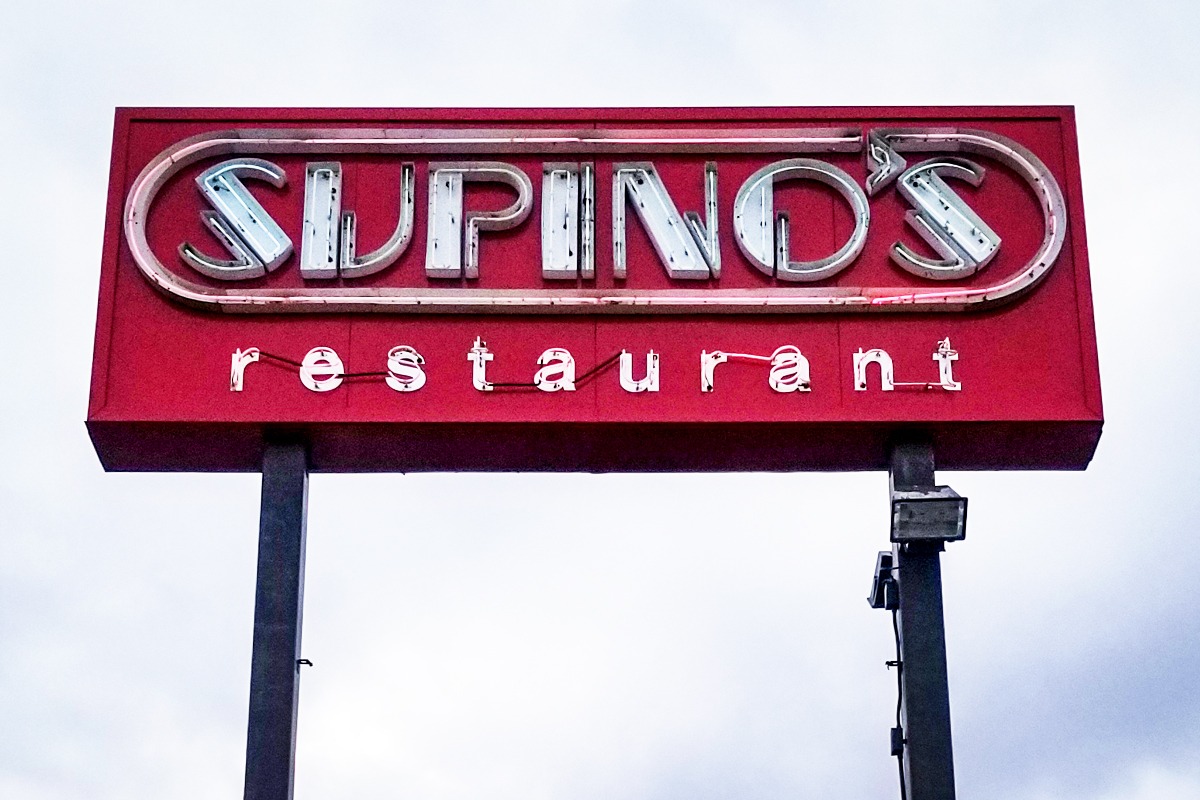 Supino's restaurant neon sign with red background and vintage-style lettering, showcasing custom neon craftsmanship by Signs East.
