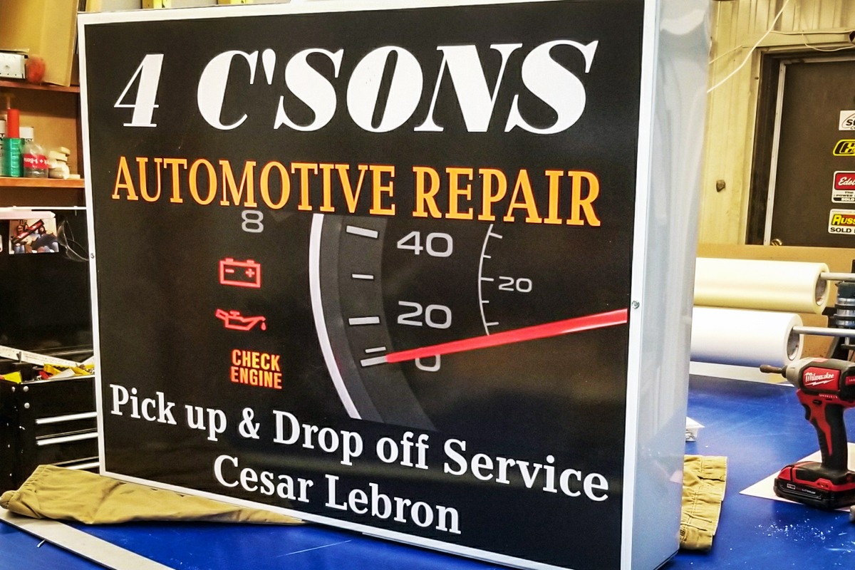 Illuminated sign for "4 C'SONS AUTOMOTIVE REPAIR" featuring a speedometer graphic and service details, highlighting custom signage by Signs East.