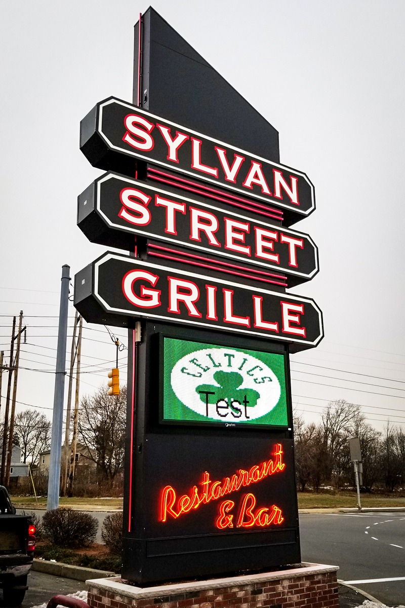 Sylvan Street Grille sign showcasing illuminated branding and digital display, highlighting restaurant and bar services in a commercial setting.