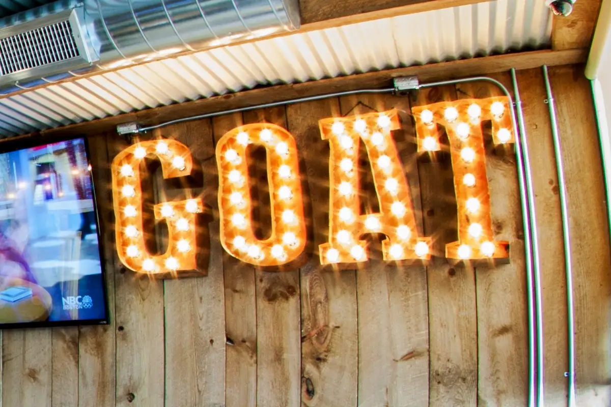 Illuminated dimensional letters spelling GOAT mounted on wooden wall