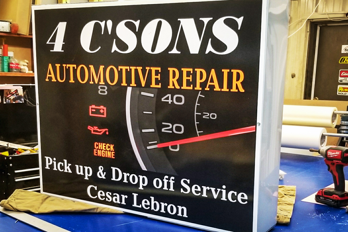 4 C'SONS Automotive Repair sign featuring a check engine light and gauge, emphasizing pick-up and drop-off service by Cesar Lebron, in a workshop setting related to sign services.