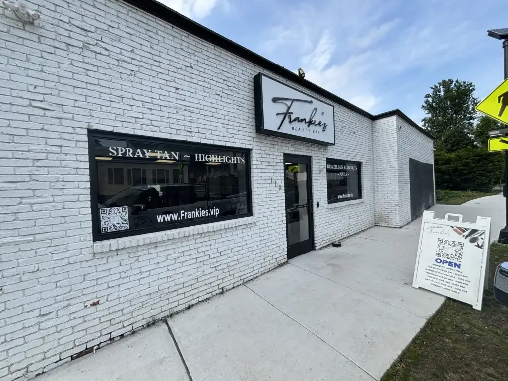 Frankie's Beauty Bar storefront featuring signage for spray tan and highlights, with a QR code and an open sign, emphasizing local service and community engagement.