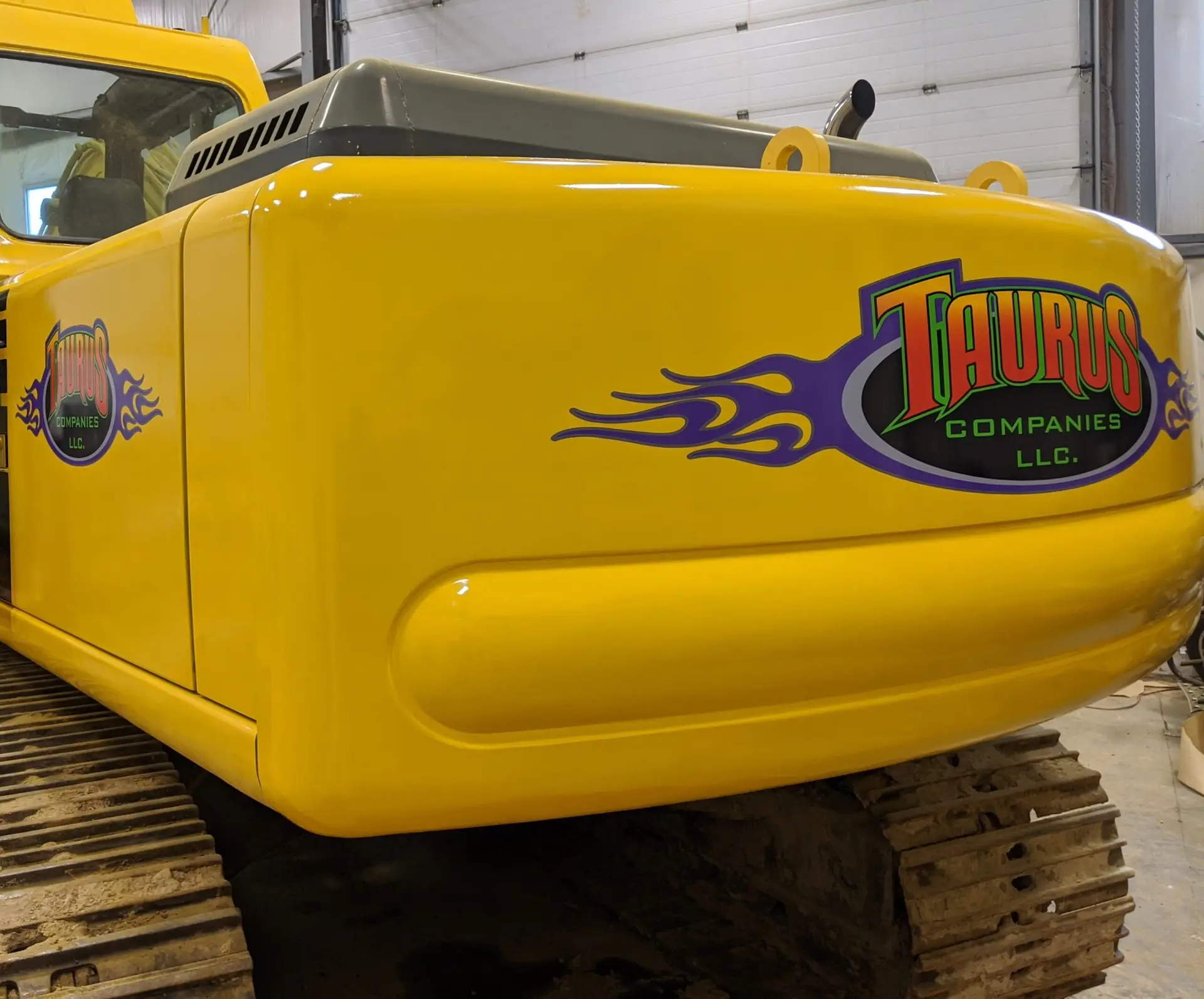 Yellow work vehicle featuring custom vinyl lettering with "TAURUS Companies LLC" and flame graphics, showcasing branding for fleet visibility.