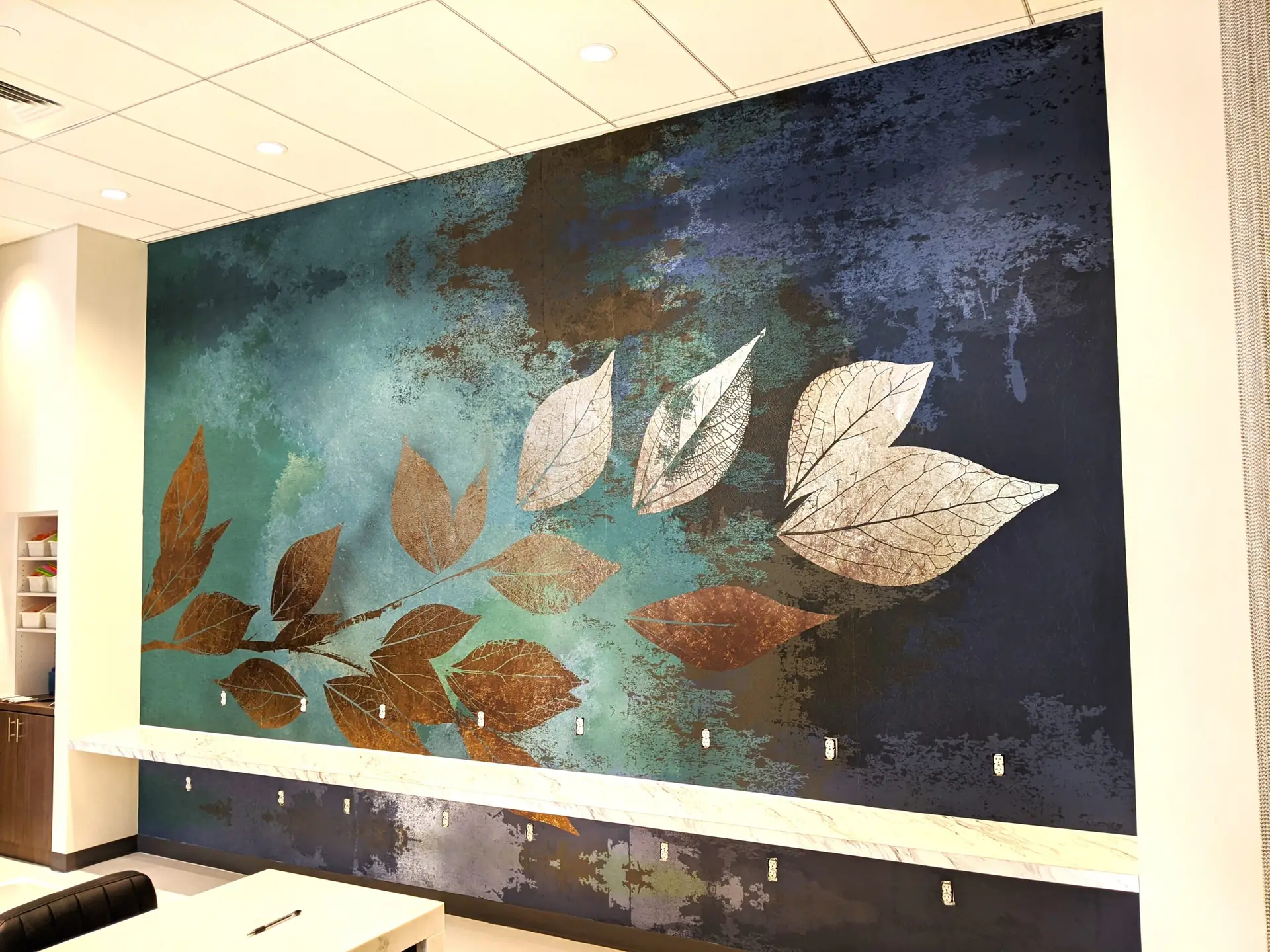 Custom wall mural featuring abstract leaves in earthy tones on a textured blue background, enhancing corporate space aesthetics.