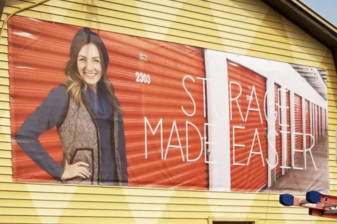 Large format banner displaying a smiling woman promoting storage solutions with the text "STORAGE MADE EASIER" against a backdrop of red storage units.