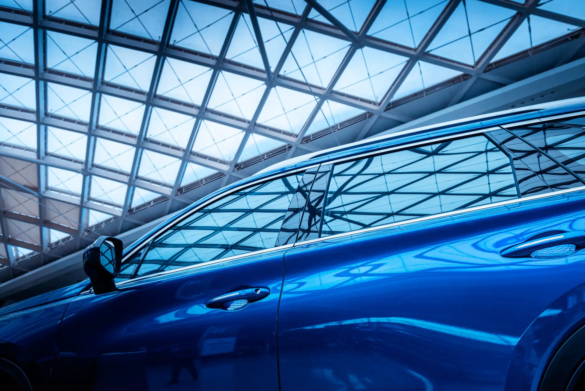 Blue vehicle with tinted windows reflecting a modern architectural ceiling, showcasing window tinting benefits for UV protection and heat reduction.