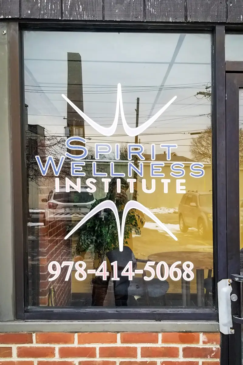 Vinyl lettering on storefront window displaying "Spirit Wellness Institute" with contact number 978-414-5068, promoting business visibility and branding.