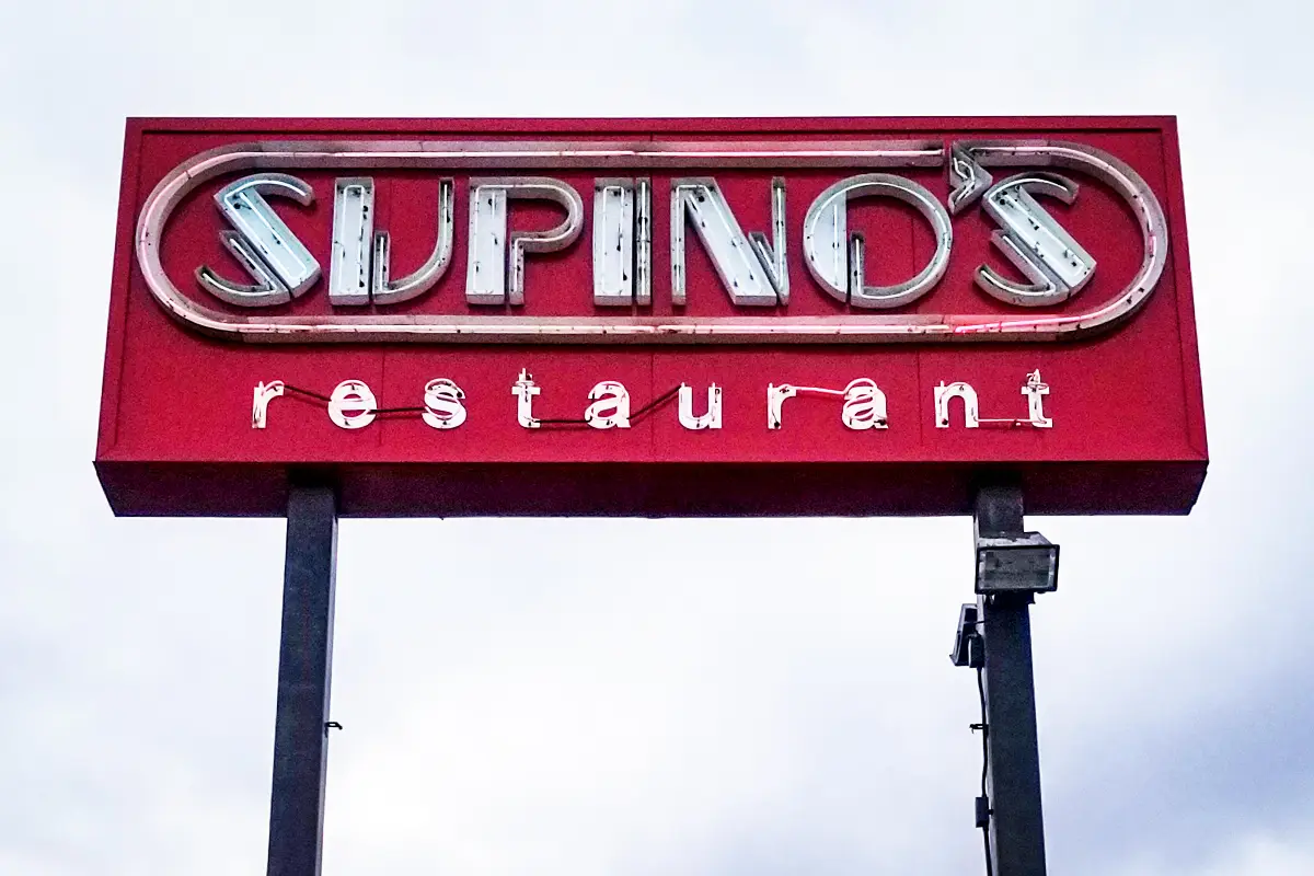 Supino's restaurant sign with vintage lettering on a red background, showcasing custom signage craftsmanship by Signs East for local businesses.