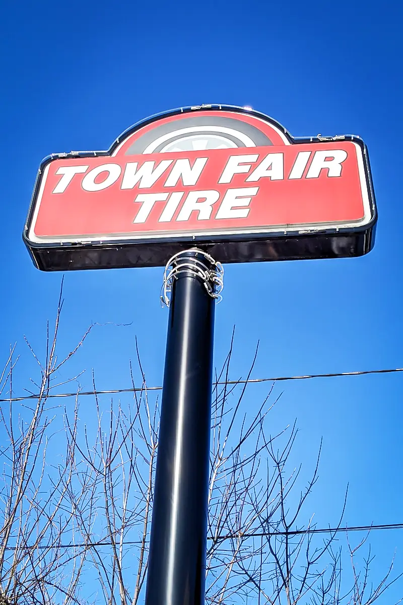 Pylon sign for Town Fair Tire with bold red background and white lettering, showcasing roadside visibility against a clear blue sky, emphasizing custom sign solutions for businesses.