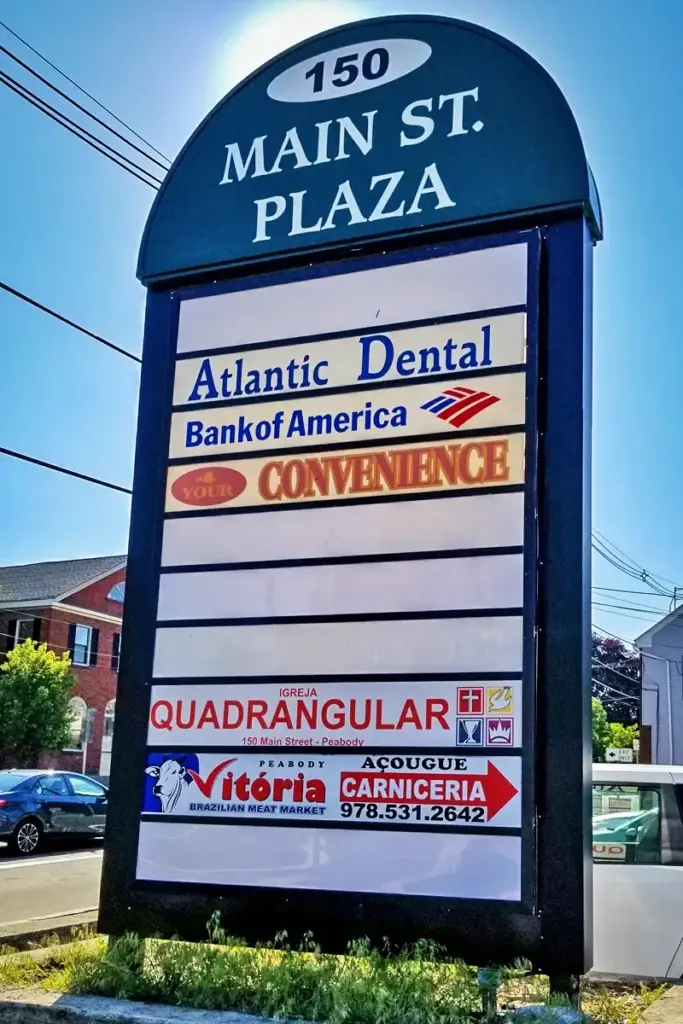 Commercial signage display at Main Street Plaza featuring Atlantic Dental, Bank of America, and Vitoria Brazilian Meat Market, emphasizing local business visibility in New Hampshire.
