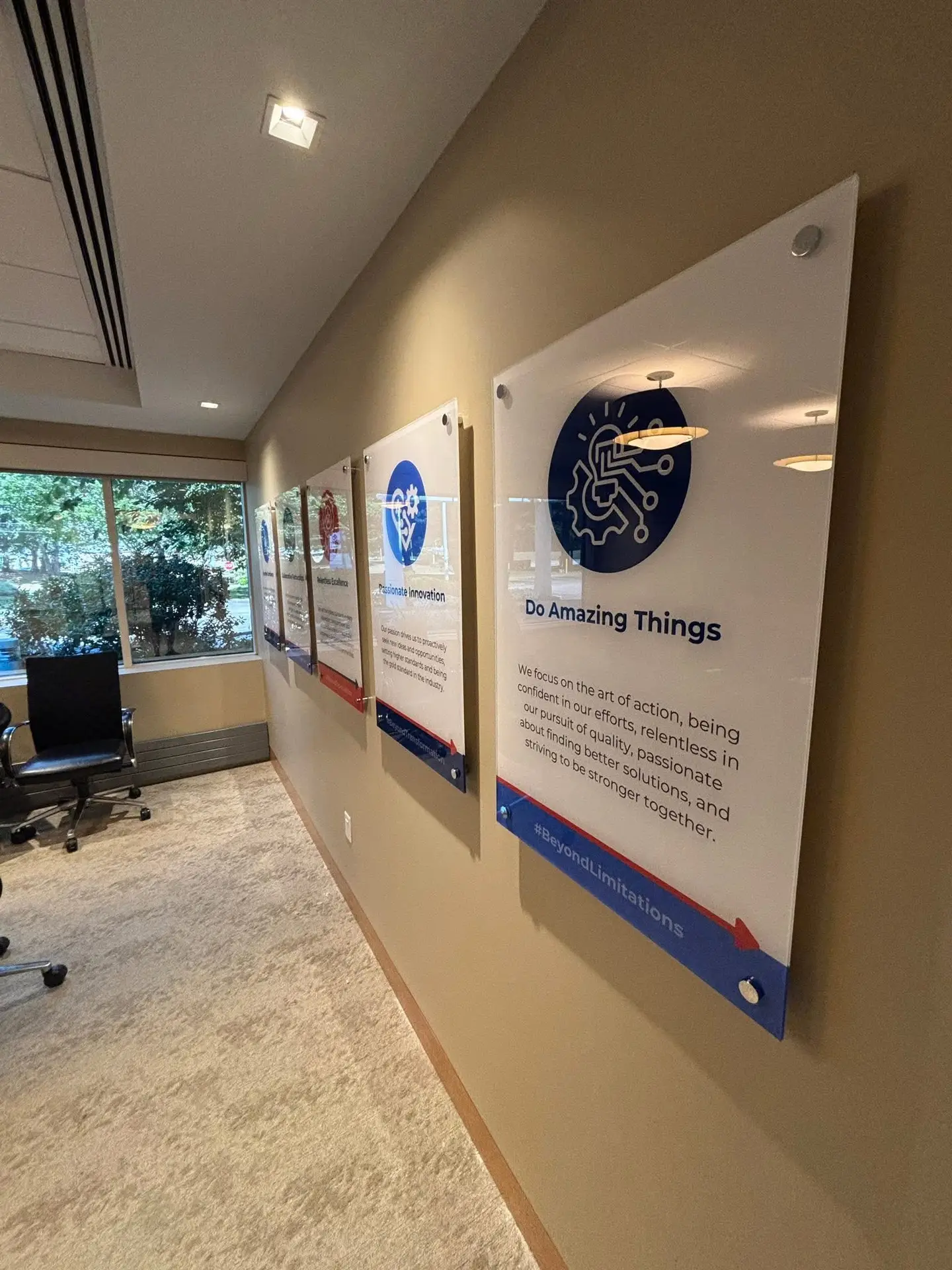 Acrylic signage displaying motivational phrases and graphics in a professional office setting, highlighting themes of innovation and collaboration.