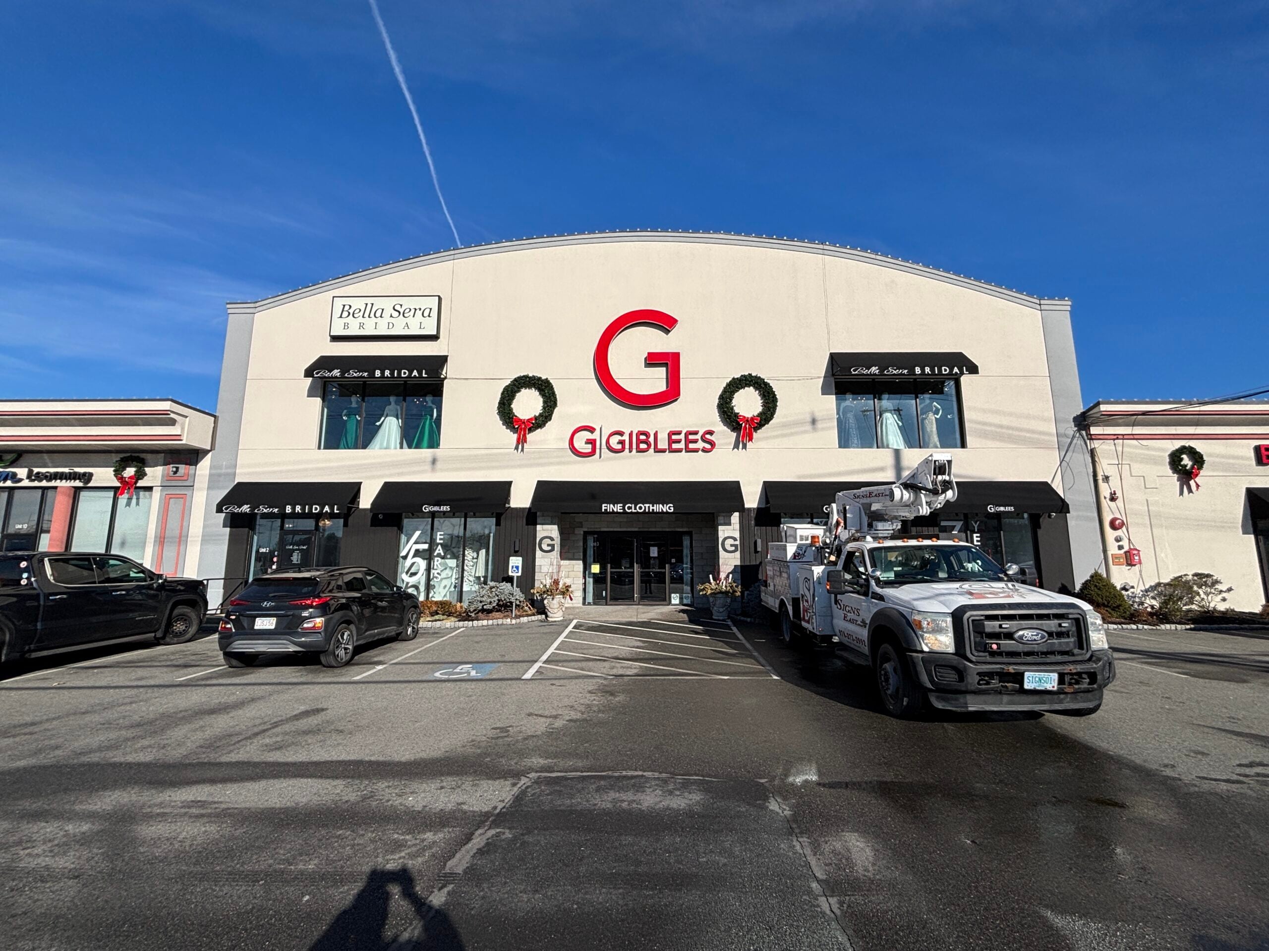 Completed installation of a custom awning sign for Giblees, showcasing the storefront with holiday decorations and a service truck from Signs East in the foreground.