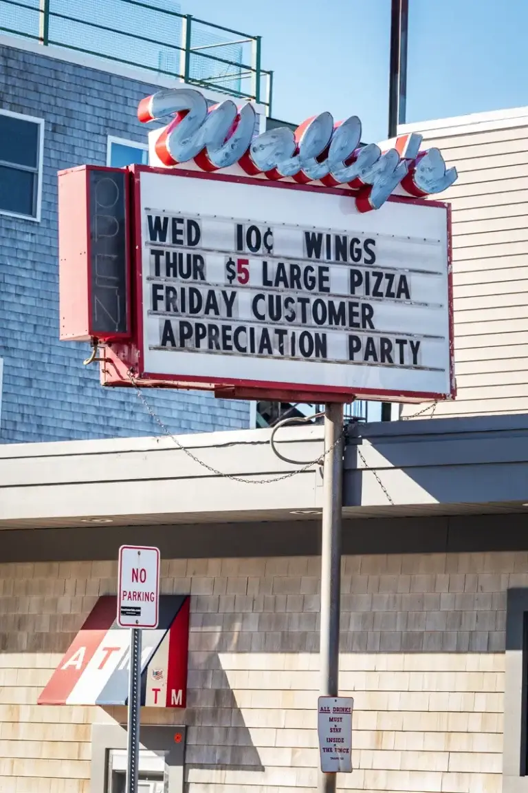 Wally's restaurant sign advertising wings, pizza specials, and appreciation party.