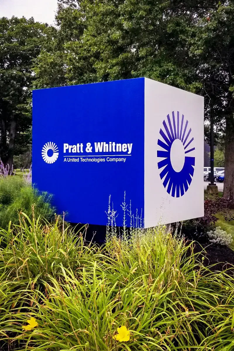 Blue and white monument sign for Pratt & Whitney, a United Technologies Company, with stylized logo.