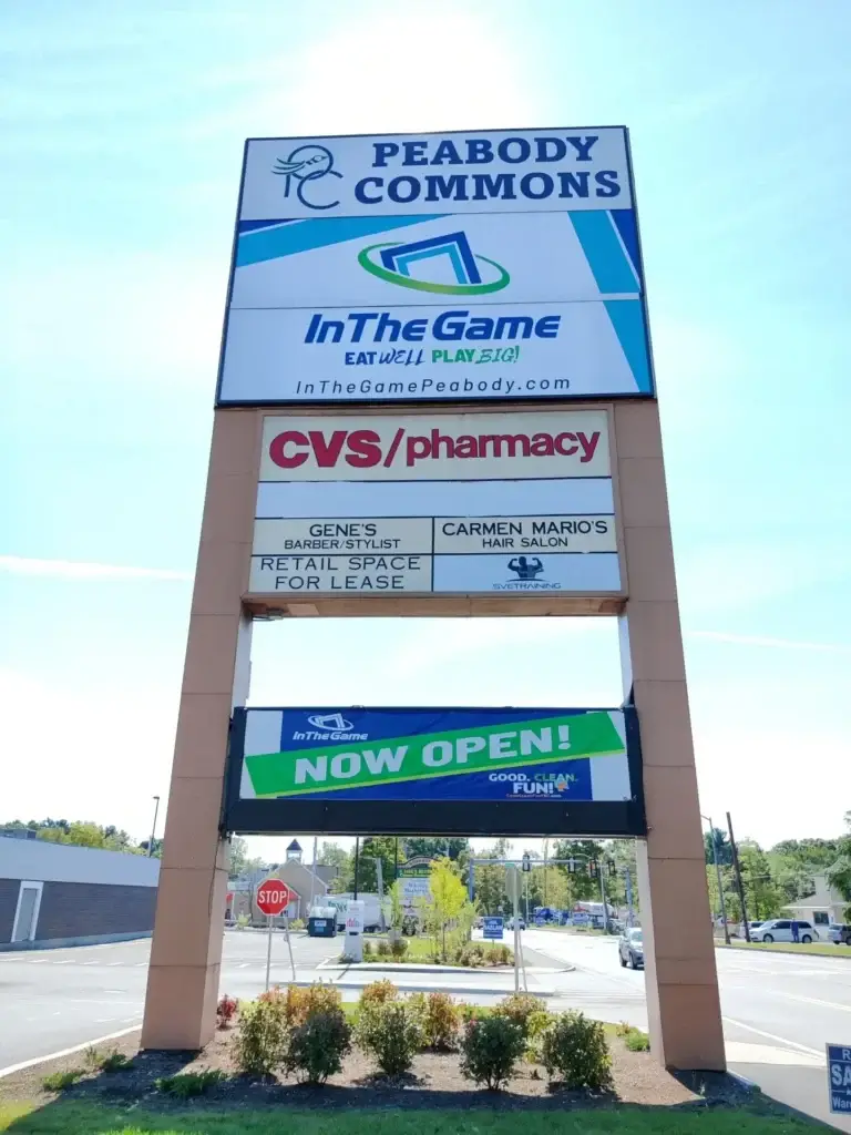 Monument sign with multiple tenant directories and "Now Open" banner, illustrating permitting challenges and site