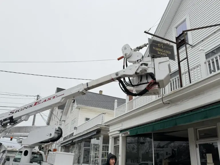 Bucket truck installing a sign for Variegated Roots on a storefront